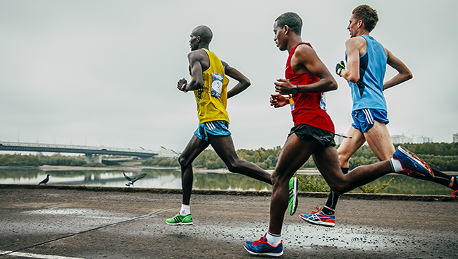 Photo of three male track runners mid stride. 