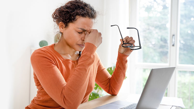 Woman with hand on eyes holding glasses