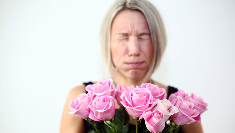 Woman with pink roses sneezing 