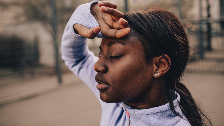 Woman wiping sweat from forehead