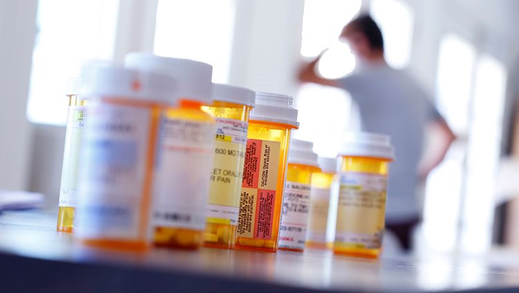 Pill bottles on table with man in the back