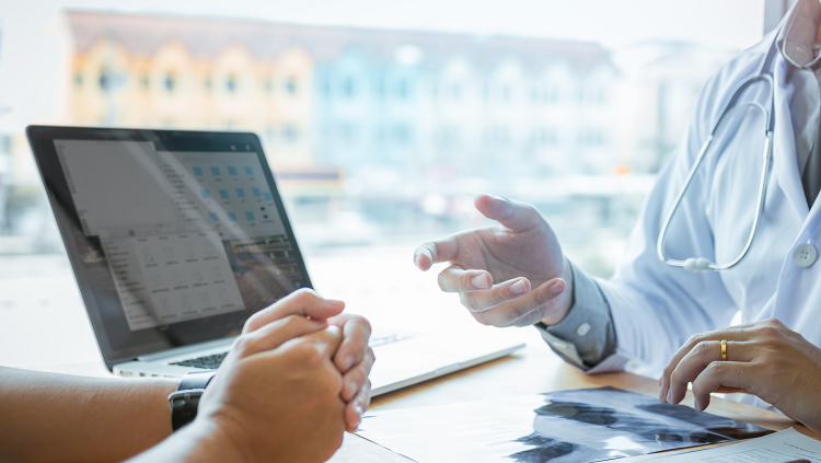 Photograph of two people's hands as they talk at an office desk