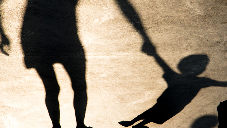 Shadows on the pavement of parent holding a child's hand