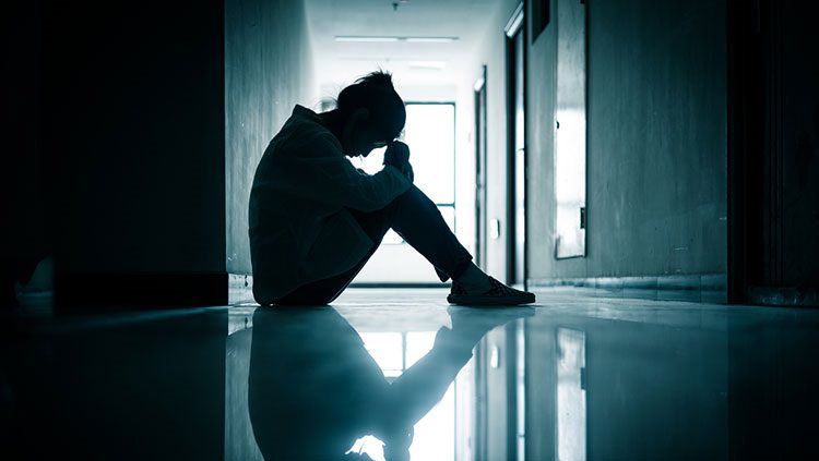 Person sitting in hallway with head down