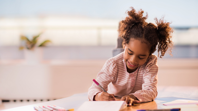 Photograph of a girl drawing happily