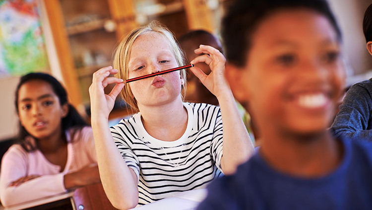 Young girl in a classroom is distracted from schoolwork