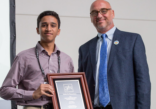 High school student Akshay Balaji, winner of the 2016 Brain Awareness Video Contest, receives his award at Neuroscience 2016 from Scott Thompson, chair of the Public Education and Communication Committee.
