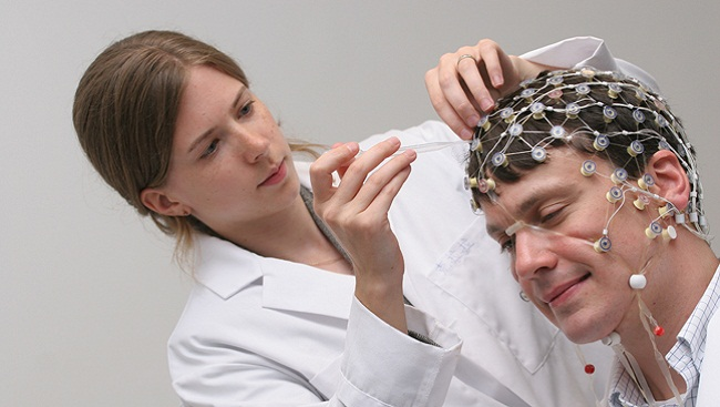 A researcher attaches electrotrodes to a man's scalp.