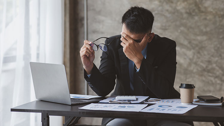 Man sitting at desk with hand on his head