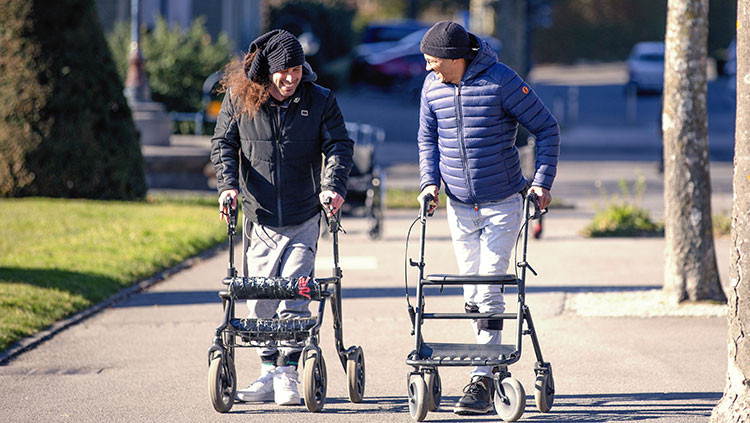 Two people walking with help of walkers