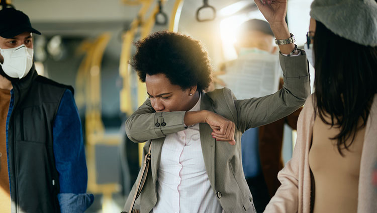 Woman sneezing in arm