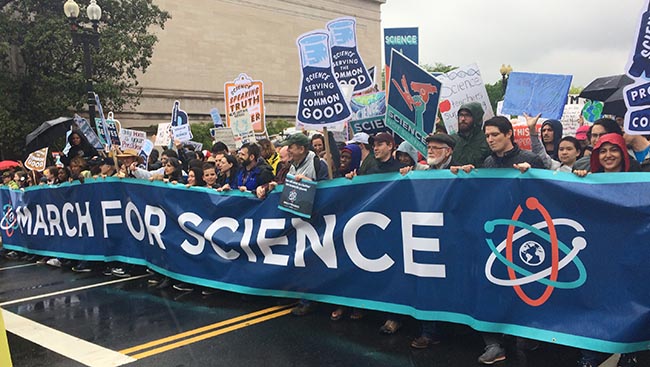 Science supporters walk with "March for Science" banner down Constitution Avenue in Washington, D.C.