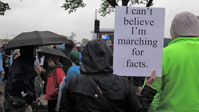 Marcher stands with a sign that reads: "I can't belive I'm marching for facts."