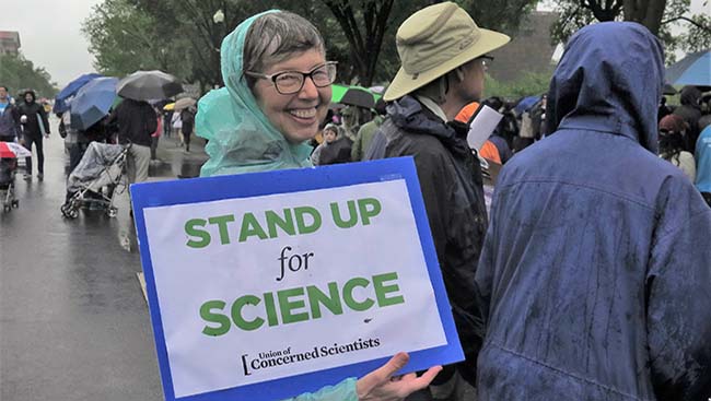 March holds a sign from the Union of Concerned Scientists that reads: "Stand Up for Science."