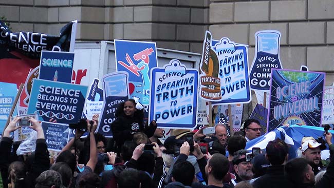 Marchers walk with various signs in support of science.