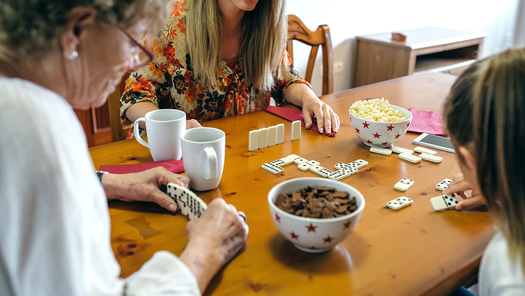 Photograph of woman with gray hair playing cards with children