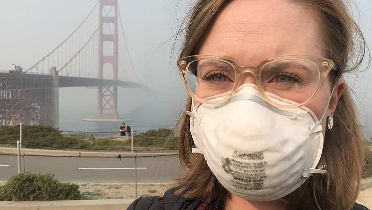 Photograph of woman with mask on in front of Golden Gate Bridge