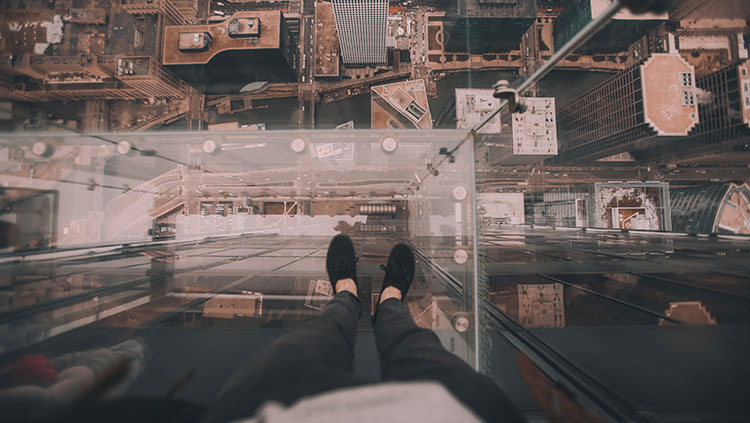 Person standing on glass platform over city