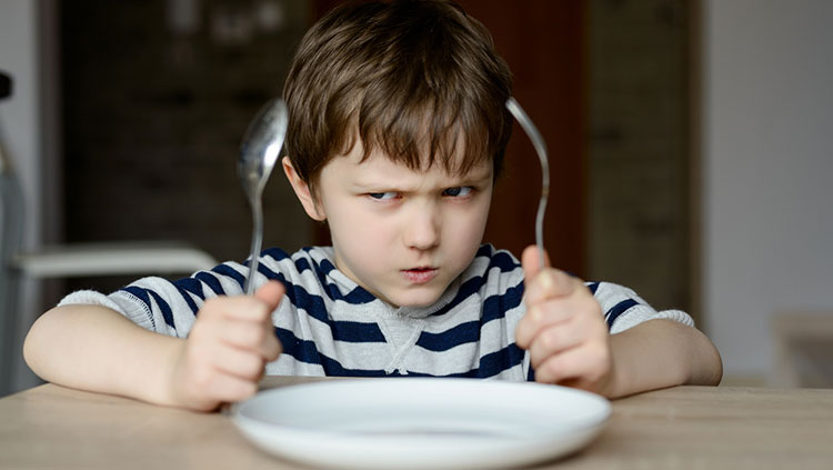 Little boy mad at dinner table