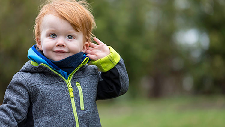 Young child holding his hand to his ear