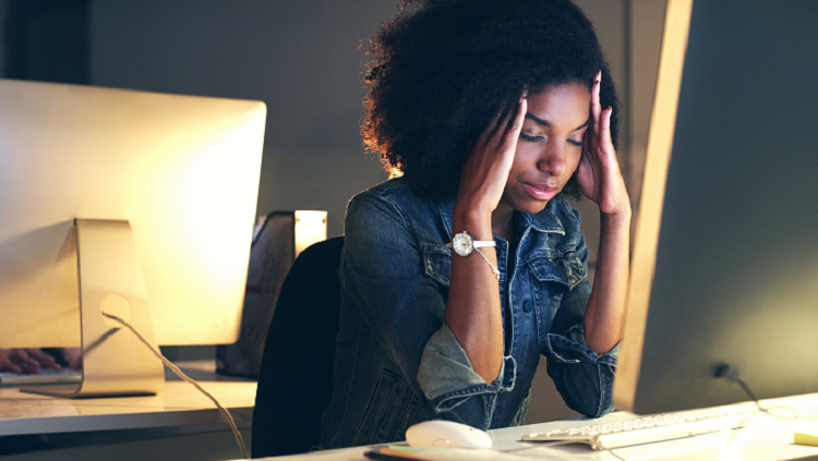 woman with a headache sitting at a computer