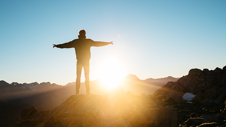 person with arms open watching the sun