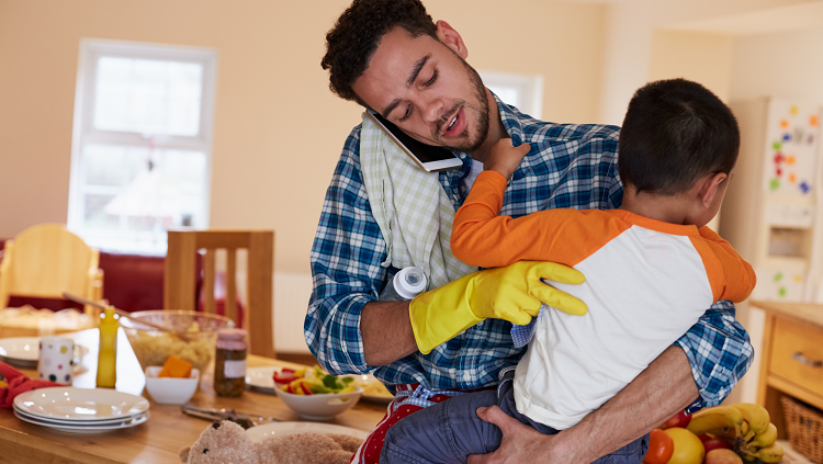 Photograph of a man cleaning and taking care of a child at the same time